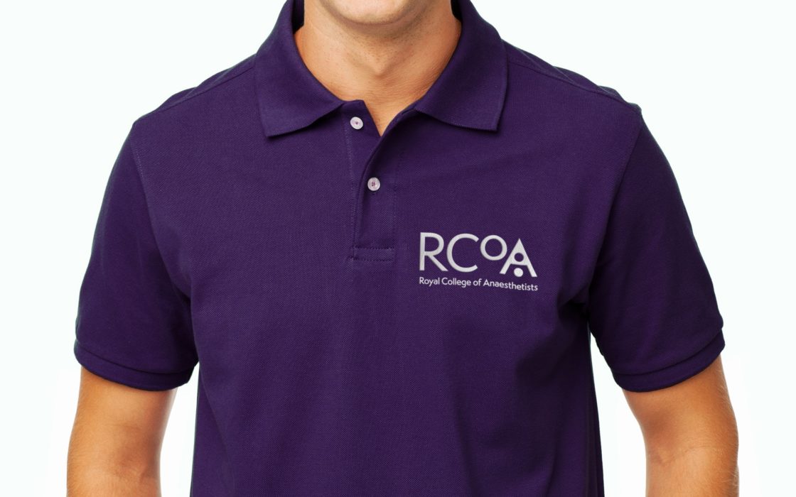 Close up of man's purple polo shirt with the RCoA logo the right.