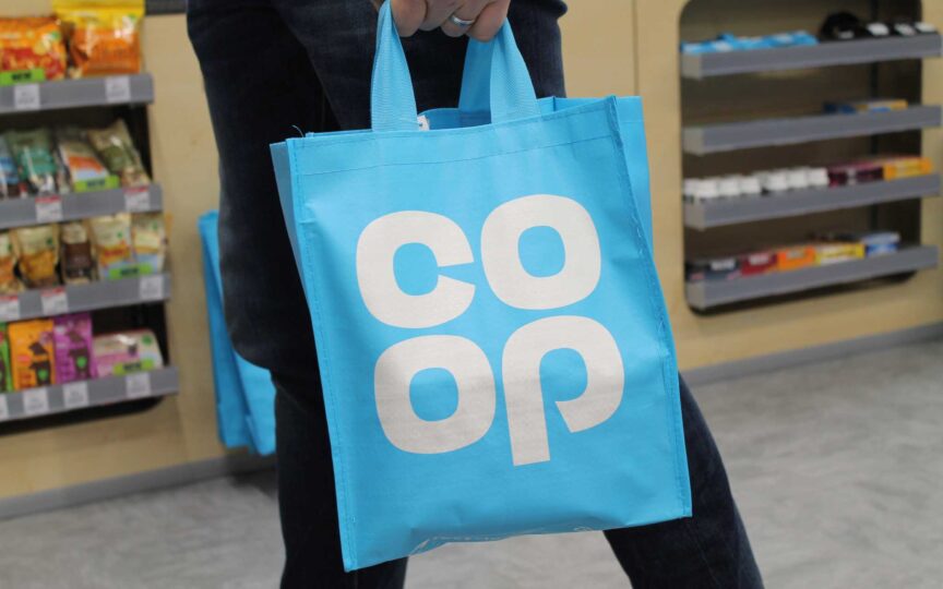 Blue Co-op shopping bag in store, illustrating the Co-operative Group’s community-driven and ethical business model.