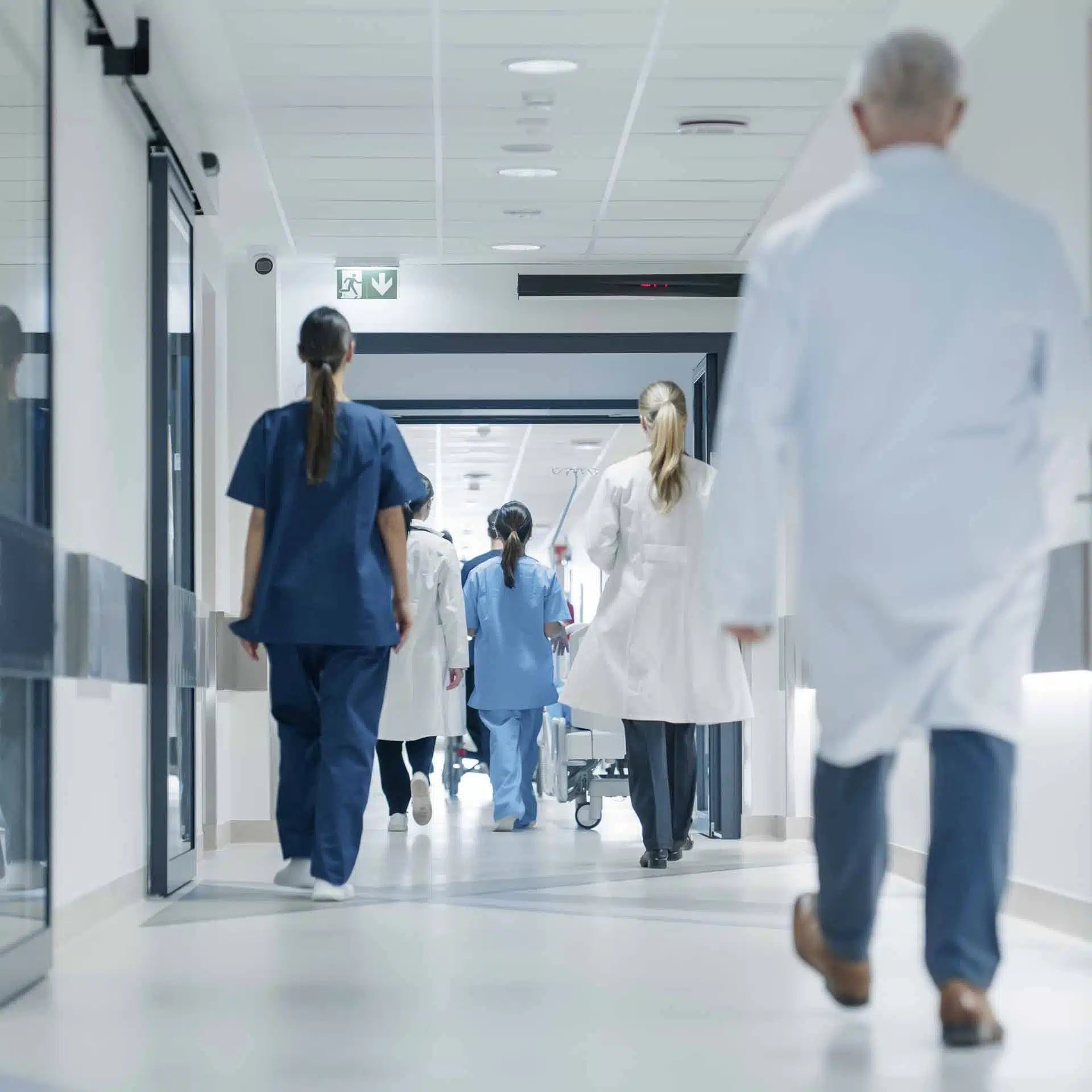 Healthcare professionals walking through a bright hospital corridor.